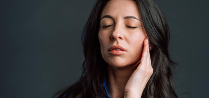 woman holding jaw due to early gum disease symptoms without pain